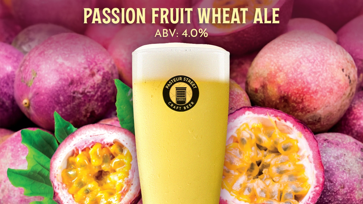 A glass of Pasteur Street Passion Fruit Wheat Ale, a fruity wheat beer, set against a background of fresh whole and sliced passion fruits.